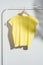 Yellow t-shirt on wooden hanger displayed on clothes rack