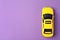 Yellow taxi car model on purple background. Space for text