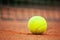 Yellow tennis ball lies on the clay court close up
