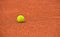 Yellow tennis ball on red clay ground court