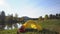 The yellow tent costs on the bank of the mountain lake. Red backpack and tourist boots.