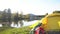 The yellow tent costs on the bank of the mountain lake. Red backpack and tourist boots.