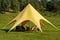 Yellow tent or marquee with chairs in green field. Outdoor activities, events, awning for relaxation