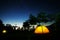 Yellow tent at night with star trails in the backgound.