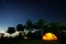 Yellow tent at night with the star trails in the background.