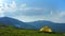 A yellow tent stands against a beautiful mountain landscape. The sun`s rays break through the clouds. Hiking in the mountains