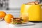 Yellow toaster with roasted bread slices, sandwich, oranges and juice on white marble table