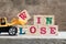 Yellow toy bulldozer hold letter block W to word win lose