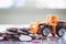 The yellow toy bulldozer with pile of coins against blurred background