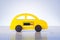 Yellow toy car with electrical battery as an electric car symbol. Eco style auto.