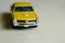 Yellow toy car on gray striped surface. Model of classic muscle car with shadows and partly soft focus. Perspective view of  auto