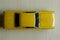 Yellow toy car on gray striped surface. Model  of classic muscle car with shadows and partly soft focus. Top view of auto