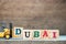 Yellow toy forklift hold letter block D to complete word Dubai