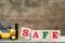 Yellow toy forklift hold letter block S to complete word safe