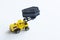 Yellow toy forklift is holding a black toy coffin in a bucket. Concept of the exhumation coffin and forensic examination. Black