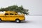 Yellow toy taxi on a tree trunk. Christmas.