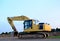 Yellow tracked excavator at a open-pit mining. Crushing and recycling on construction site. Road work.