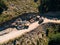 Yellow tracked tractor loads a quarry vehicle with sand. View from drone