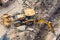 Yellow tractor with a bucket and back and front, digging a trench at a construction site. View from above