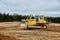 A yellow tractor bulldozer stands in a sand pit