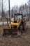 yellow tractor among the trees in the open air on a farm without a driver. Front view. Agricultural machinery.