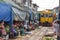 The yellow train has arrived while people are taking pictures and videos at Maeklong Railway Market.