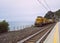 Yellow train parked in front of the ocean in Corniglia, Italy.