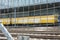 Yellow train seen through iron fence with railtracks