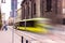 Yellow tram with motion blur effect moves fast in the city. High speed passenger train in motion on railroad. Modern urban rail