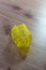 Yellow translucent plastic Hanukkah dreidel on a wood table, Hebrew letter Gimel facing up