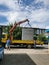 Yellow truck crane and workers on loading electrical switchboard durinfg sunny day