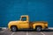 Yellow truck parked in front of blue wall, copy space