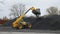 Yellow truck pushing coal use hydraulic excavator with gripper