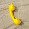 Yellow tube of old vintage phone lies on the sand asand symbol of communication