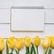 Yellow tulips bunch on white wooden planks rustic barn rural table background. Empty space for lettering, text, letters,