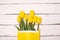 Yellow tulips bunch on white wooden planks rustic barn rural table background. Empty space for lettering, text, letters,