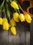 Yellow tulips and guitar on old wood surface. Small depth of fie