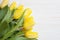 Yellow tulips on white wood background. Spring - poster with free text space.