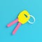 Yellow two keys on keyring on bright blue background in pastel colors