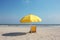 Yellow umbrella and beach background with empty yellow sunbeds.