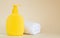 Yellow unbranded dispenser bottle next to white towel on beige background