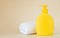 Yellow unbranded dispenser bottle with white towel on beige background