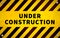 Yellow under construction warning sign with metal screws in corners