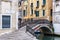 Yellow Venetian street corner with an arch railed bridge.