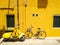 Yellow Vespa and a bicycle on a background of a yellow wall.