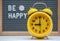 yellow vintage alarm clock on the background of a gray felt Board with the inscription in English be happy