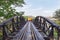 Yellow vintage passenger thai train moving across on river Kwai bridge Thailand.