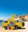 Yellow Vintage, Retro, Old-fashioned mini bus van camper VW T2 with surfboard on beach, cliff, palm tree