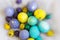Yellow, violet, blue and green Easter egge with had drawings of butterflies, polka dots, spirals