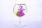 Yellow and violet paints fall in a wineglass with water
